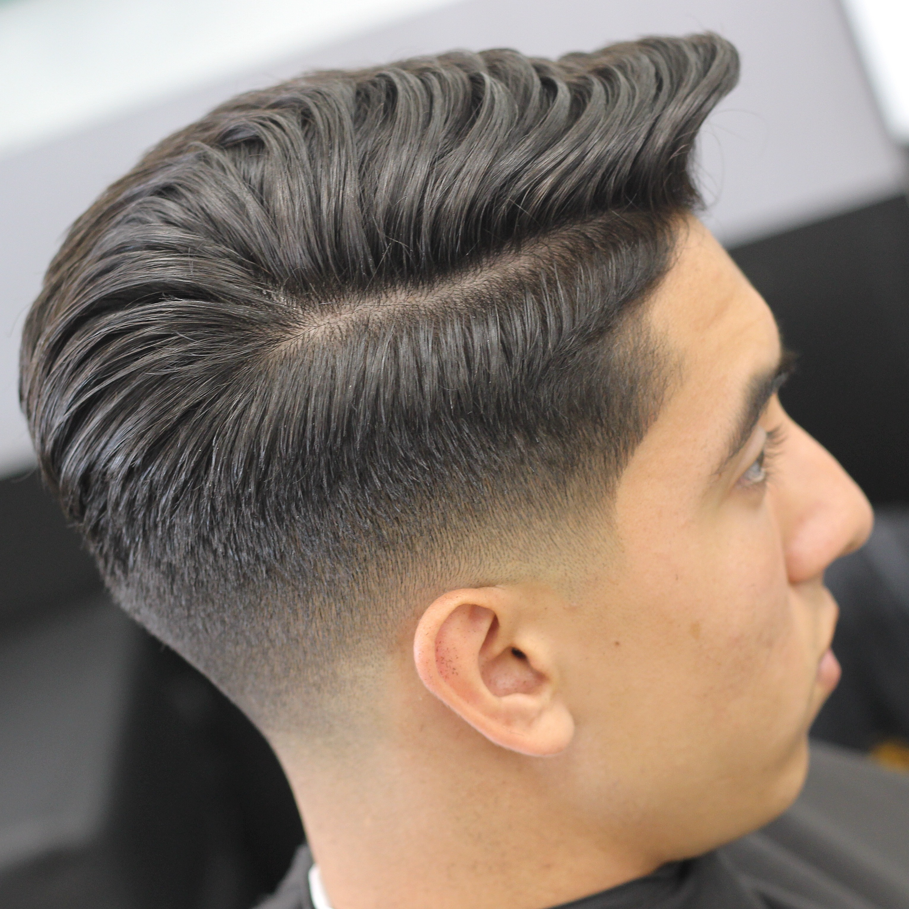 Male classic hair style with mid-fade and side part with wavy top designed by Andis barbering tools.