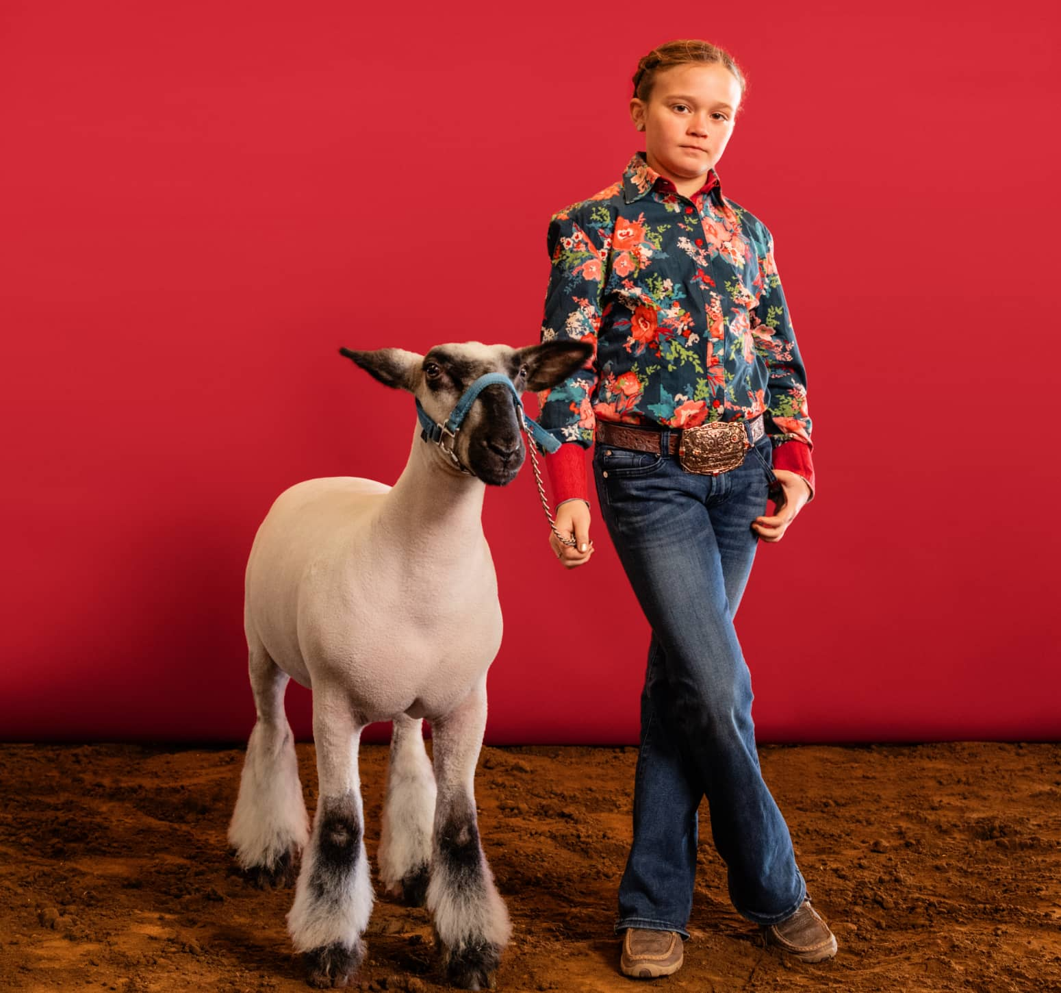 Girl standing next to animal with red background