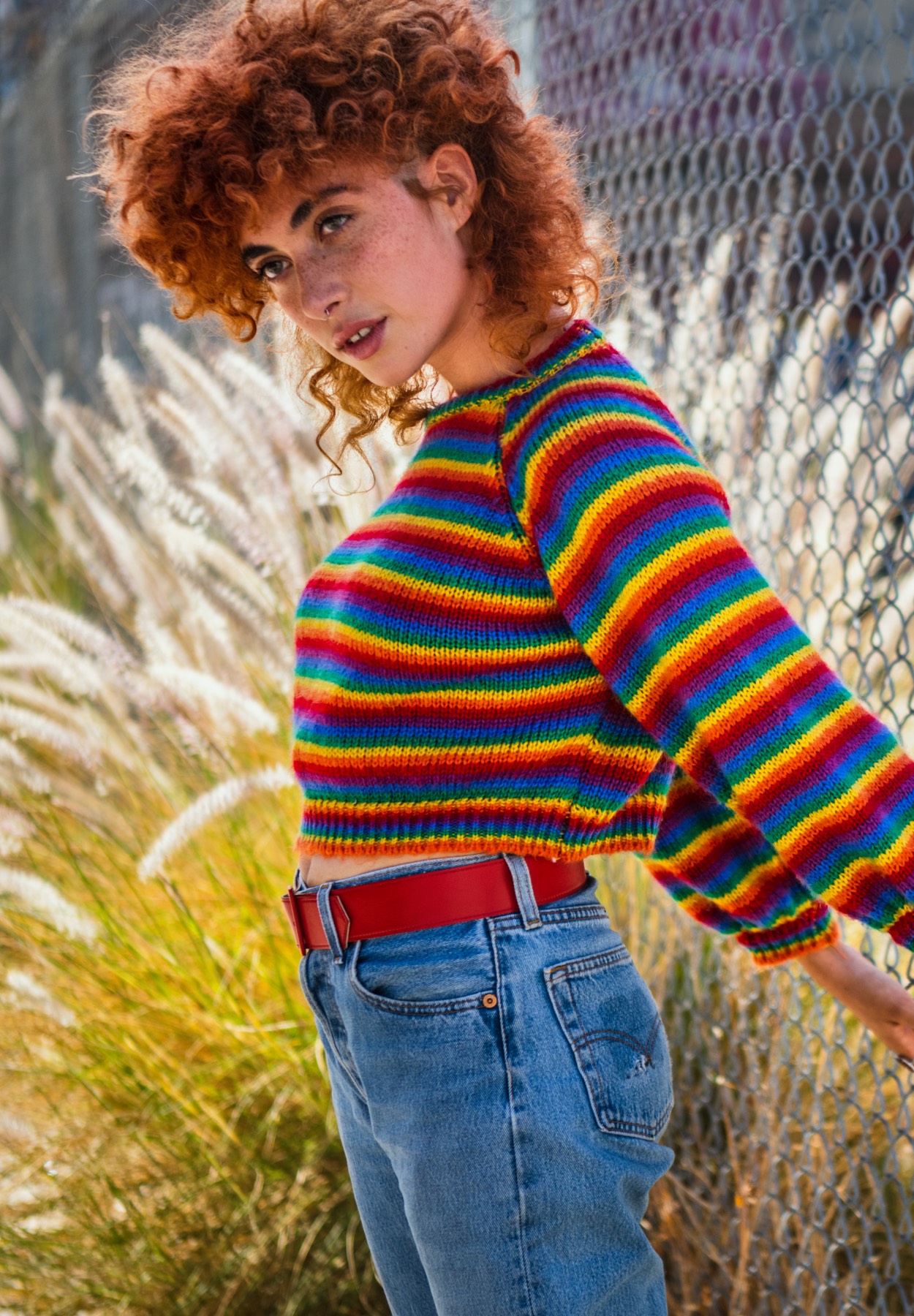 Small image of woman standing with rainbow sweater